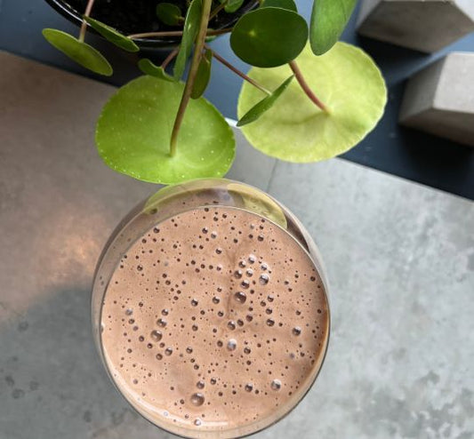Herbalife-banan-sjokoladeshake i et glass på en kjøkkenbenk.