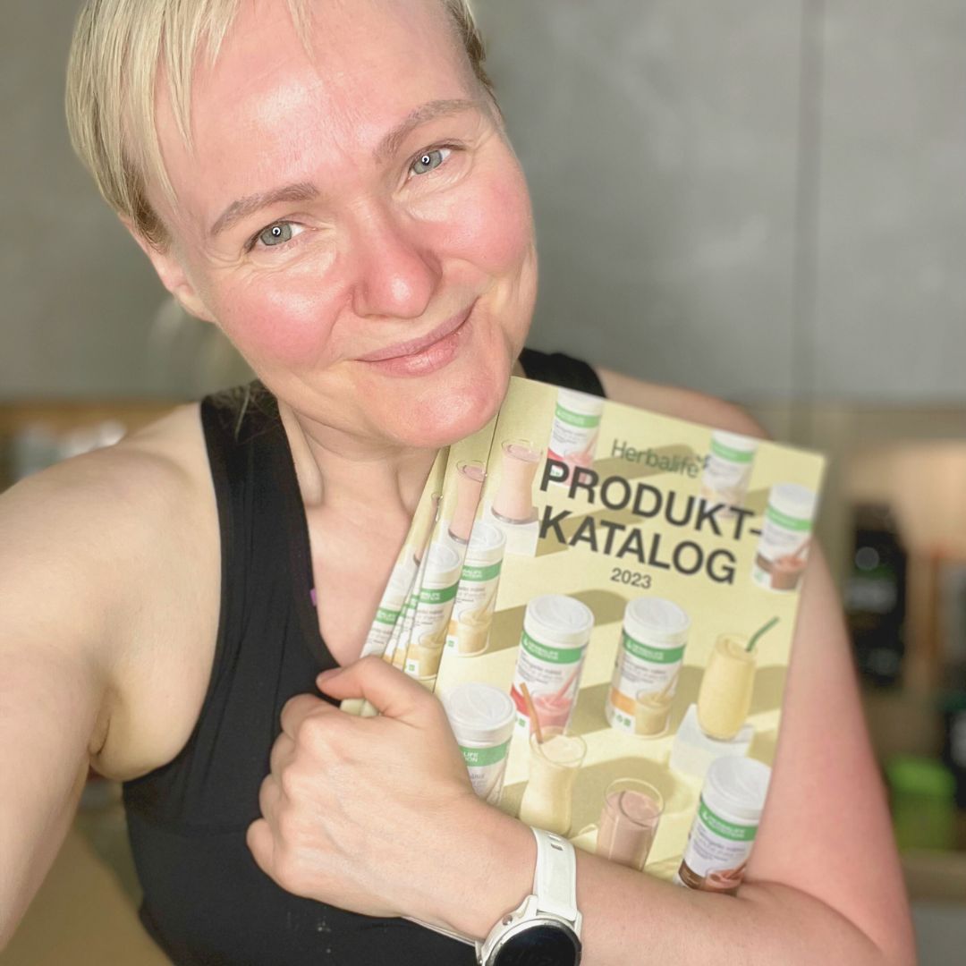 En kvinne holder en bunke Herbalife produktkataloger.