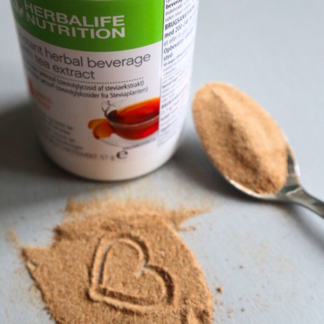 Herbalife instant urtete med skje og tepulver formet som et hjerte - energigivende drikk med naturlig smak og ekstrakt fra grønn te og stevia.