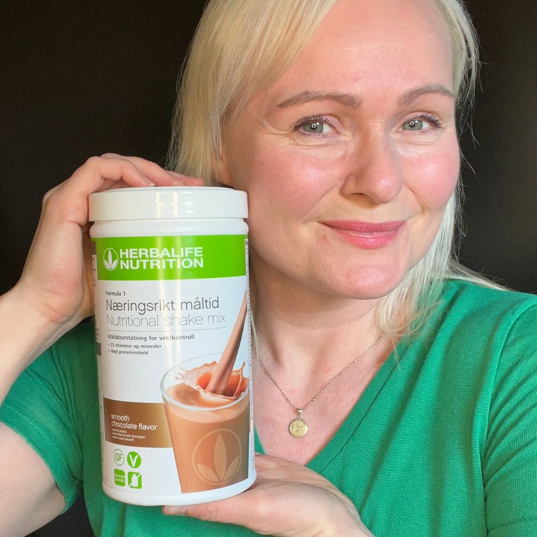 En boks Herbalife Formula 1 shakemix med Smooth Chocolate-smak og Helga som viser den frem.