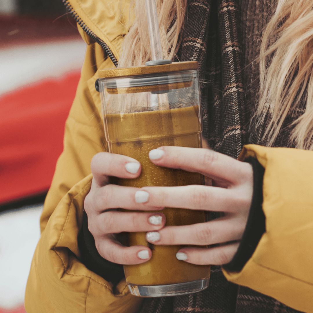En vinterkledd kvinne holder et glass-tumbler med Herbalife protein-iskaffe.