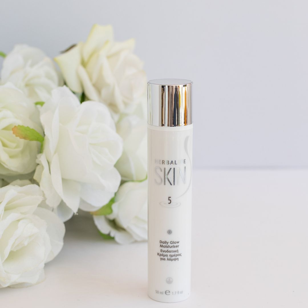 En tube Herbalife SKIN Daily Glow Moisturiser dagkrem og en bukett hvite roser.