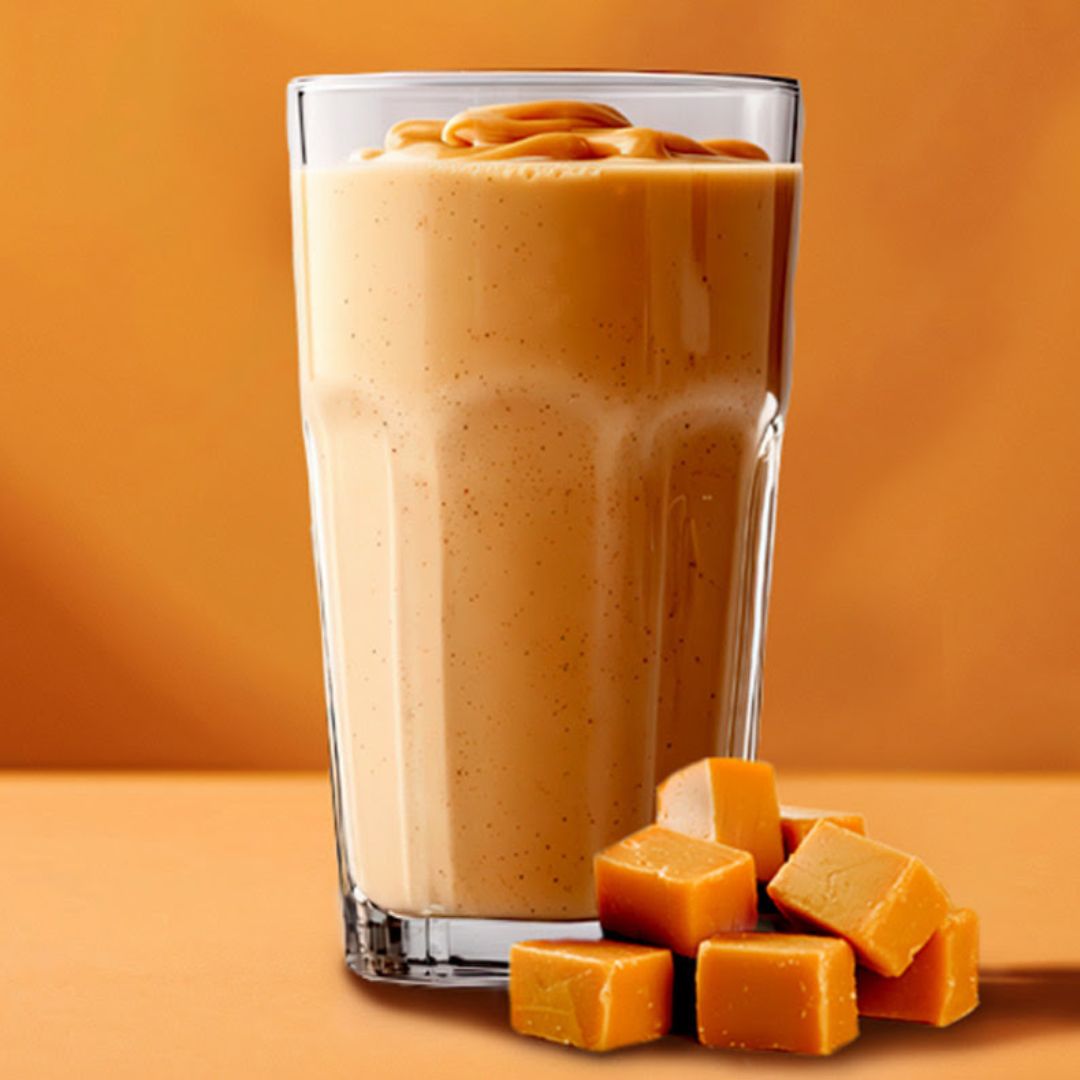 Salt karamell-shake i et stort glass, karameller ved siden av.