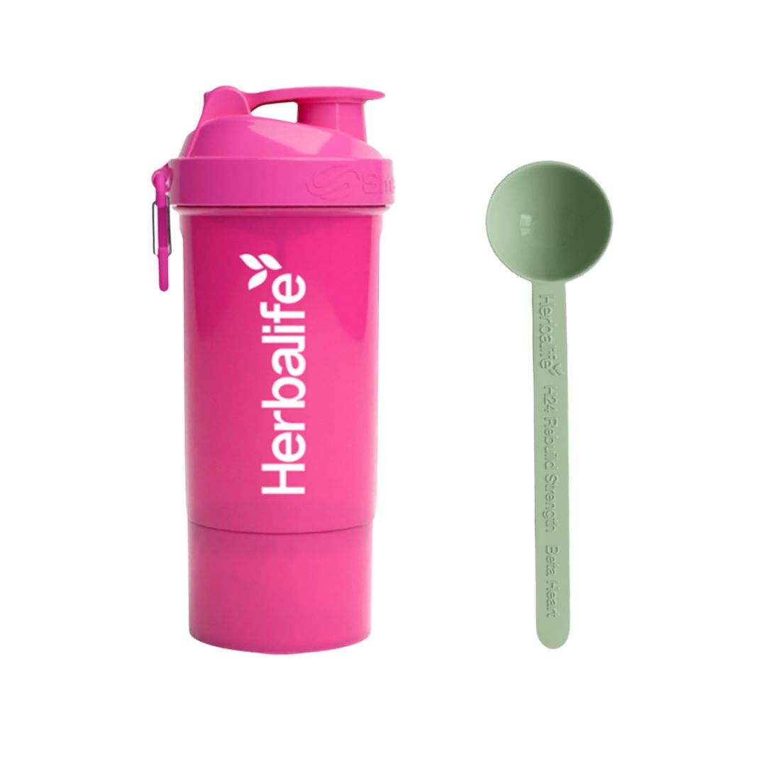 Rosa Herbalife SmartShake 600 ml med hvit logo og karabinkrok, plassert ved siden av en lysegrønn Herbalife-måleskje. Produktfoto på hvit bakgrunn.