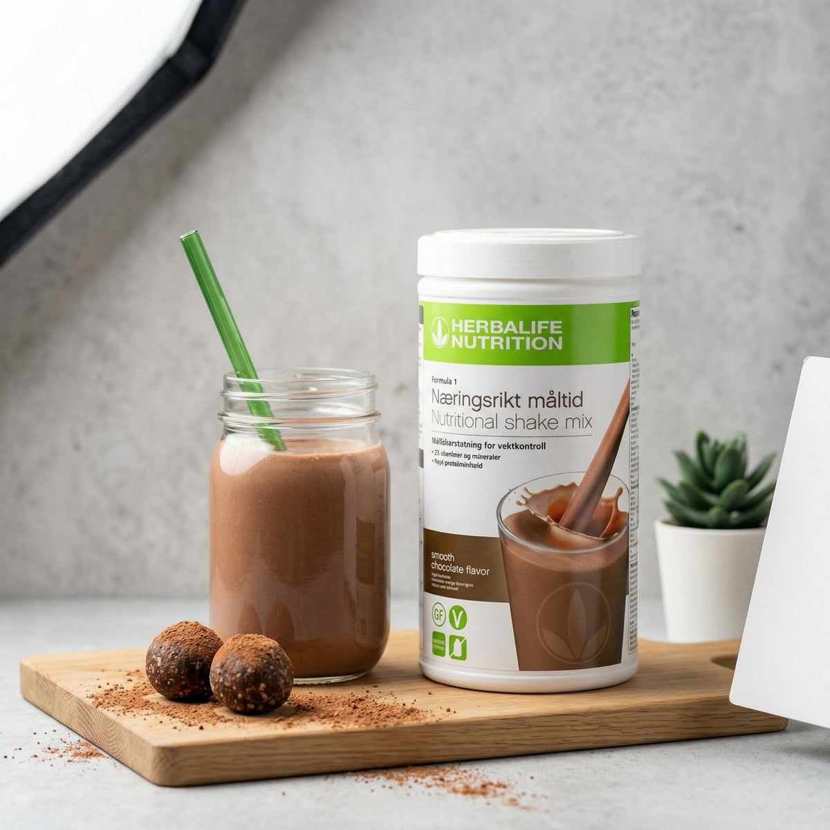 Herbalife sjokoladeshake servert i glass på trebrett med sjokoladebiter