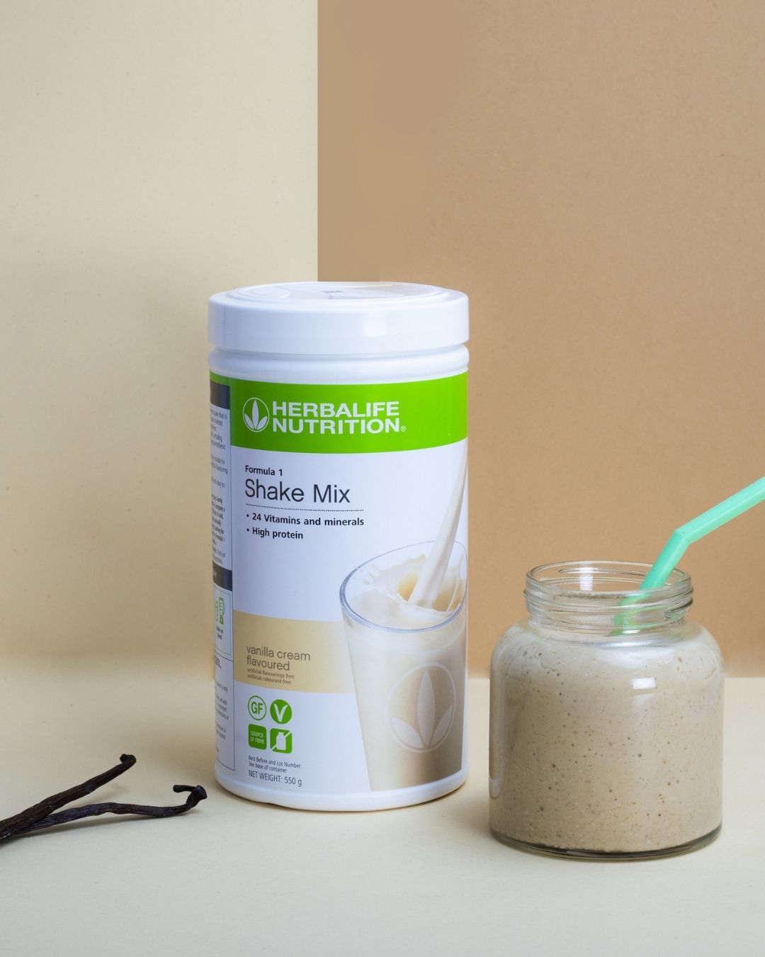 Boks Herbalife Formula 1 shakemix med vaniljesmak i midten, glasskrus med smoothie og mintgrønt sugerør og to vaniljestenger.