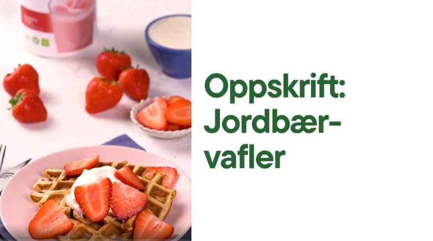 En tallerken med en belgisk vaffel toppet med gresk yoghurt og oppskåret jordbær. I bakgrunnen skimtes en boks Herbalife Formula 1 shakemix strawberry delight. Tekst: Oppskrift Jordbær-vafler. 