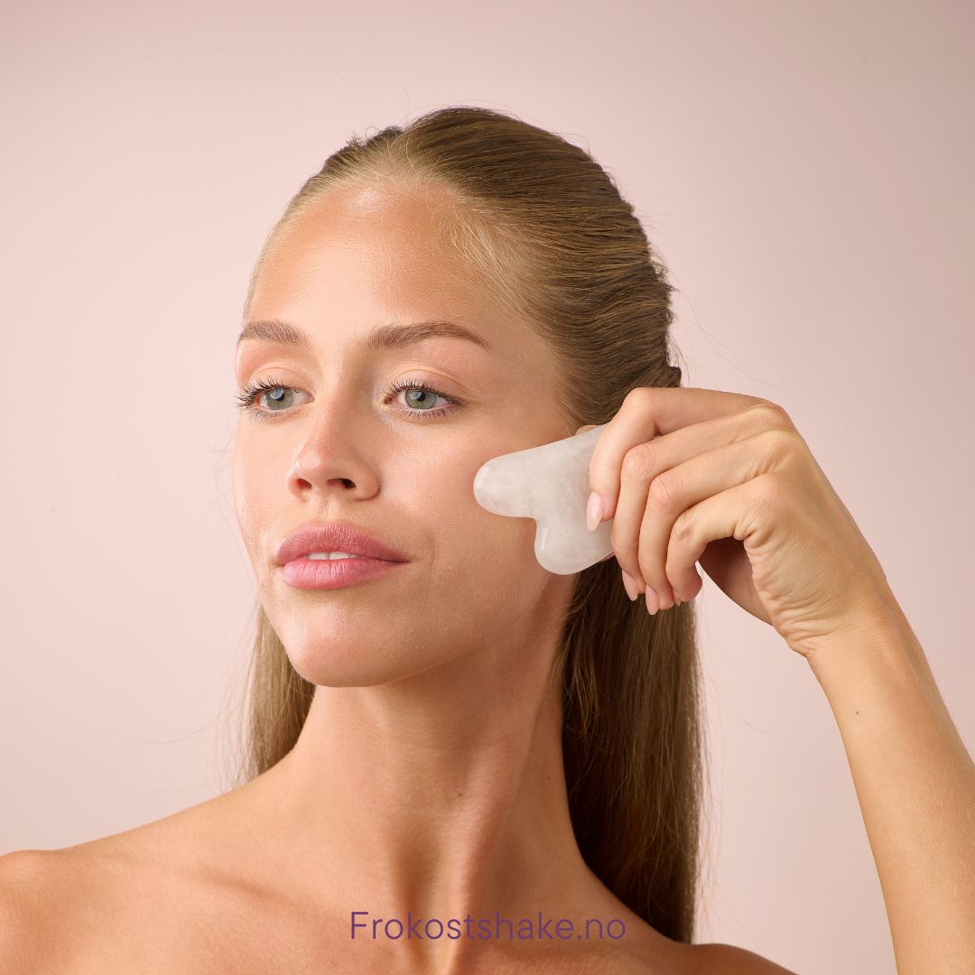 Kvinne bruker Herbalife HL/Skin Gua Sha i hvit jade til ansiktsmassasje. Beroligende og glødgivende hudpleierituale fra Frokostshake.no.