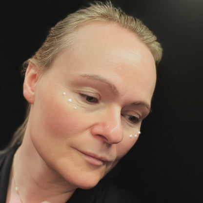 Nærbilde av kvinne som påfører HL/SKin Nourishing Eye Cream - små kremprikker under øynene,  for fukt og glattere hud.