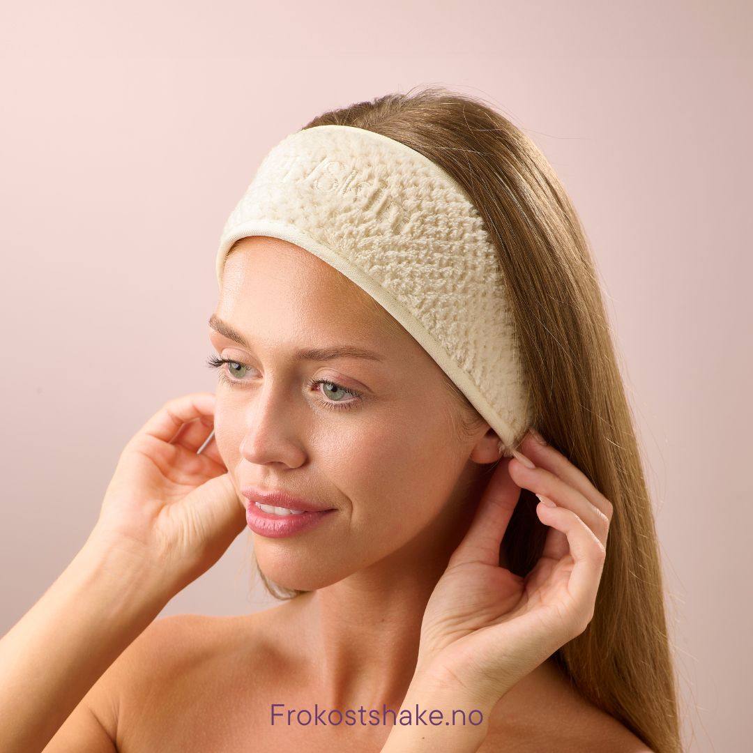 Kvinne justerer Herbalife HL/Skin hårbånd i myk bomull før hudpleierutinen. Komfortabelt og elastisk hårbånd fra Frokostshake.no som holder håret unna ansiktet.