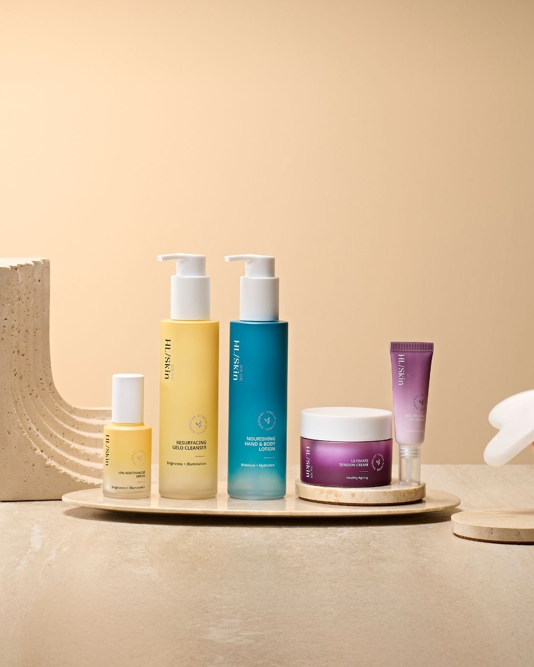 HL/Skin hudpleieserie fra Herbalife vist på beige bakgrunn med cleanser, serum, lotion, krem, øyekrem og Gua Sha. Koreansk hudpleie for fukt, glød og sunn hud.
