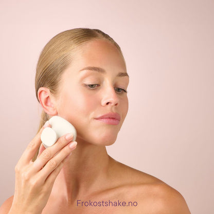 Kvinne renser ansiktet med Herbalife HL/Skin silikonbørste for ansiktsrens. Myk, hvit børste i silikon som masserer og rengjør huden skånsomt.