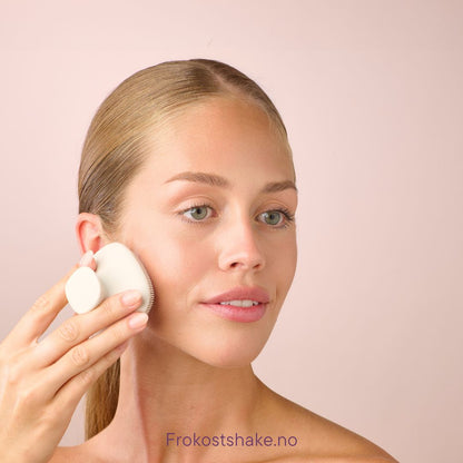 Kvinne bruker Herbalife HL/Skin silikonbørste langs kjevepartiet. Hudpleierutine med myk børste som renser og stimulerer huden for glød.