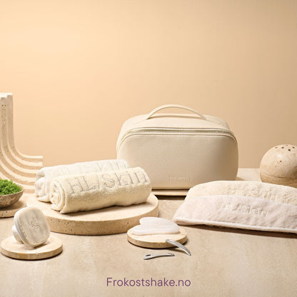 HL/Skin toalettmappe i vegansk skinn sammen med håndklær, hårbånd, Gua Sha, spatler og ansiktsbørste. Komplett hudpleietilbehør fra Herbalife på Frokostshake.no vist på benk.