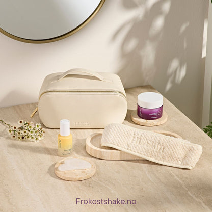 HL/Skin toalettmappe i vegansk skinn sammen med hårbånd, Gua Sha-stein, serum og ansiktskrem. Elegant oppsett på baderomsbenk som viser hudpleietilbehør fra Herbalife på Frokostshake.no.
