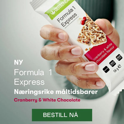 En hånd holder frem en Herbalife Expressbar Tranebær og hvit sjokolade. Bildet har teksten “NY Formula 1 Express Næringsrike måltidsbarer Cranberry & White chocolate. Bestill nå”