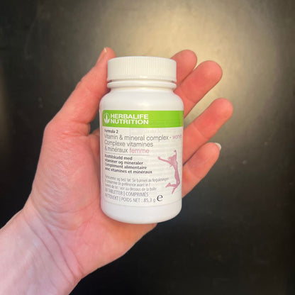 En boks Herbalife Formula 2 Multivitamin & mineraler Kvinne i hånda.