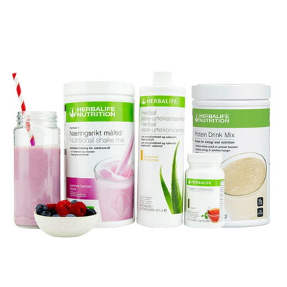 Herbalife Frokostpakke Optimal frokost summer berries; Herbalife-shake med sommerbær-smak, Herbal Aloe aloevera-juice med mangosmak, Instant urtete med original-smak og Proteindrinkmiks, samt en Herbalife-shake i et glass med sugerør og noen friske jordbær, bringebær og blåbær i en skål.