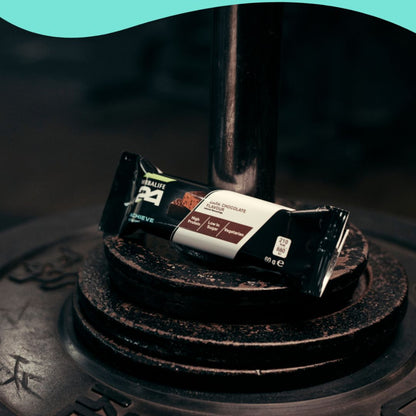 Herbalife H24 Achieve Protein Bar i smaken mørk sjokolade, plassert på vektskiver - perfekt snack etter trening med høyt proteininnhold og lavt sukkerinnhold.
