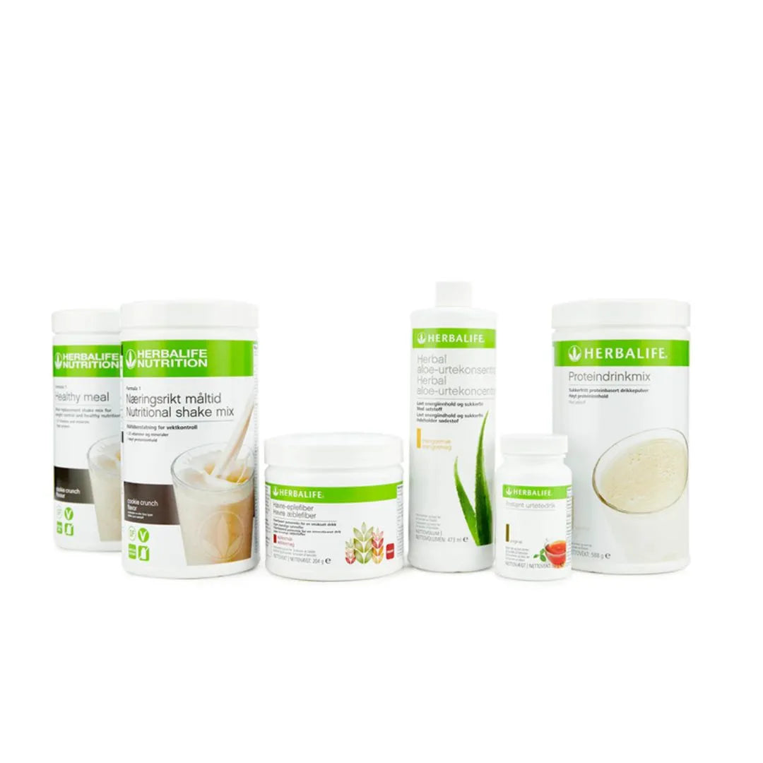 Bildet viser Herbalife-produktene som Frokostpakke vektkontroll-pakke cookie crunch består av: To bokser Herbalife-shake med cookie crunch-smak, Herbal Aloe aloevera-juice med mangosmak, Instant urtete med original-smak, havre-eplefiberdrikk og Proteindrinkmiks.   