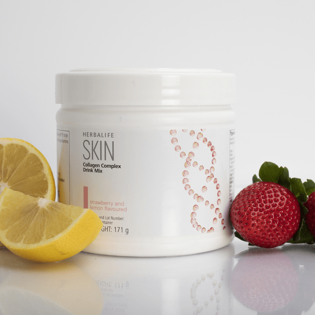 En boks Herbalife SKIN Collagen Booster står på et bord sammen med to jordbær og en oppskjært sitron. 