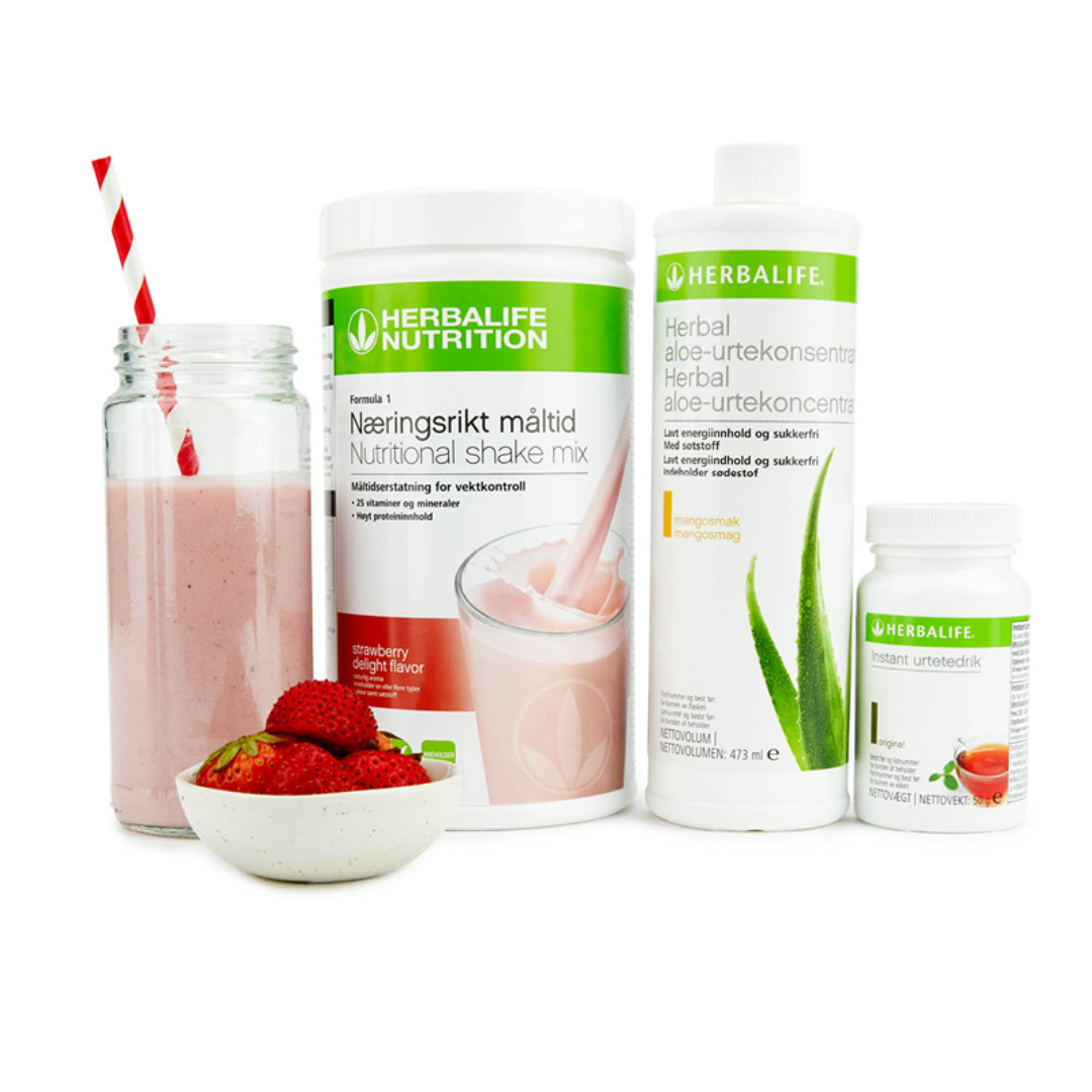 Bildet viser Herbalife-produktene som Frokostpakke basic jordbær består av; Herbalife-shake med jordbærsmak, Herbal Aloe aloevera-juice med mangosmak og Instant urtete med original-smak samt en jordbærshake i et glass med sugerør og noen jordbær i en skål.