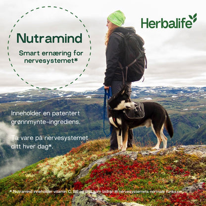 En kvinen på tur i fjellet med hund. Herbalife-logo. Teksten "Nutramind. Smart ernæring for nervesystemet. Inneholder en patentert grønnmynte-ingrediens. Ta vare på nervesystemet ditt hver dag. Inneholder vitamin C, B6 og B12 som bidrar til nervesystemets normale funksjon."