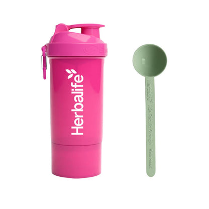 Rosa Herbalife SmartShake 600 ml med hvit logo og karabinkrok, plassert ved siden av en lysegrønn Herbalife-måleskje. Produktfoto på hvit bakgrunn.