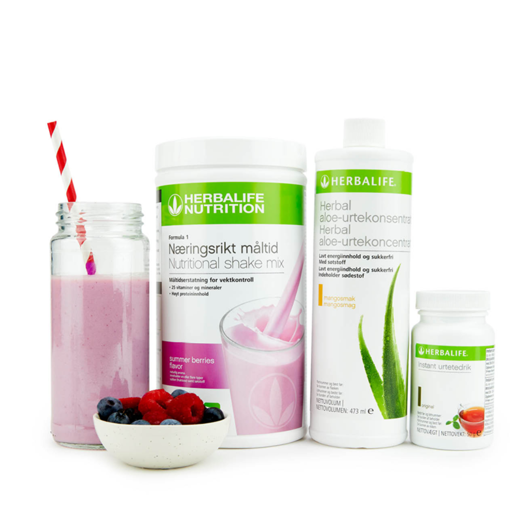 Bildet viser Herbalife-produktene som Frokostpakke basic summer berries består av; Herbalife-shake med sommerbær-smak, Herbal Aloe aloevera-juice med mangosmak og Instant urtete med original-smak samt en Herbalife-shake i et glass med sugerør og noen friske jordbær, bringebær og blåbær i en skål.