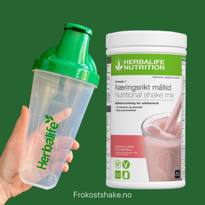 Bringebær og hvit sjokolade soyafri Herbalife shake-boks og shakerflaske i hånden på grønn bakgrunn, Frokostshake.no. 