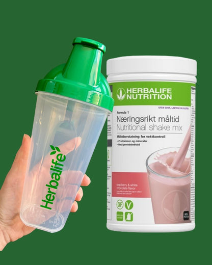 Bringebær og hvit sjokolade soyafri Herbalife shake-boks og shakerflaske i hånden på grønn bakgrunn, Frokostshake.no. 