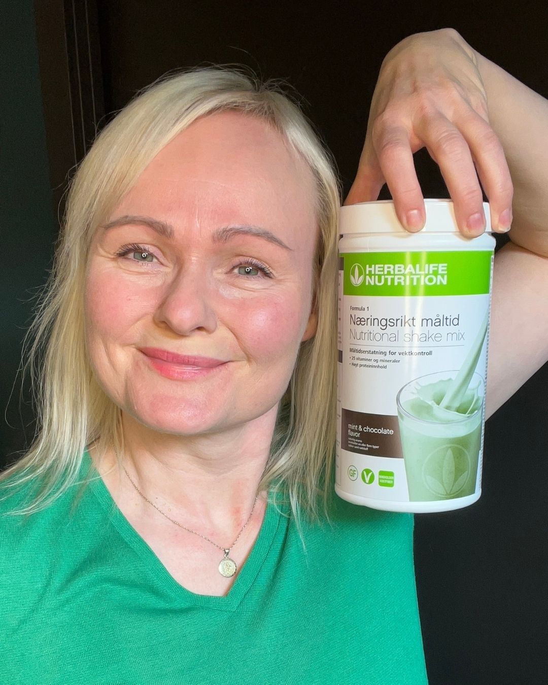 Helga holder Herbalife Formula 1 mintssjokolade boks og smiler mot kamera