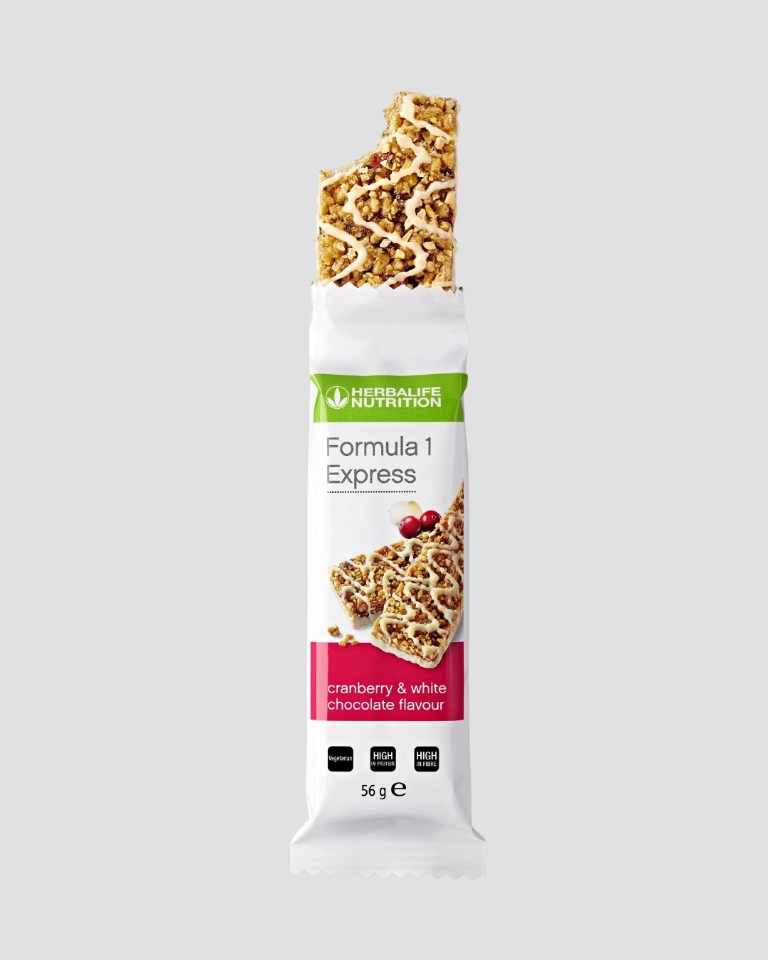En Herbalife Formula 1 Express måltidsbar tranebær og hvit sjokolade i papir, trukket halvveis ut og tatt en bit av. Grå bakgrunn.