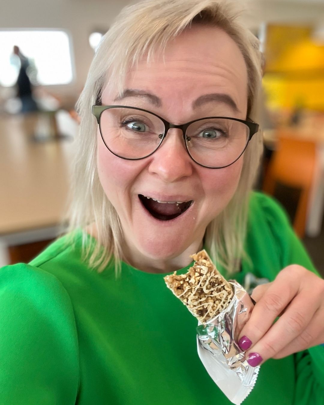 Helga i grønn kjole som spiser en Herbalife Formula 1 Expressbar måltidsbar Tranebærsmak - Cranberry & White Chocolate flavor