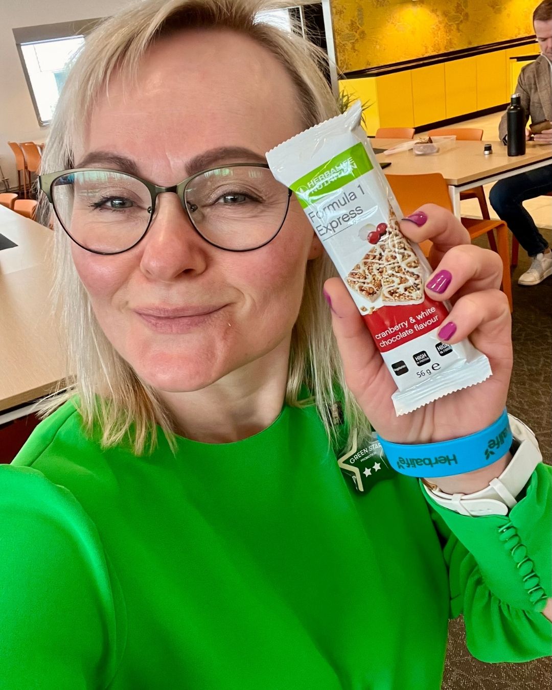 Helga i grønn kjole og en Herbalife Formula 1 Expressbar måltidsbar Tranebærsmak - Cranberry & White Chocolate flavor