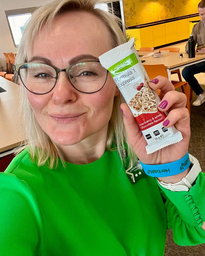 Helga i grønn kjole og en Herbalife Formula 1 Expressbar måltidsbar Tranebærsmak - Cranberry & White Chocolate flavor