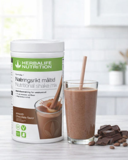 En boks Herbalife sjokoladeshake og en smoothie i et glass med sjokoladestrøssel ved siden av