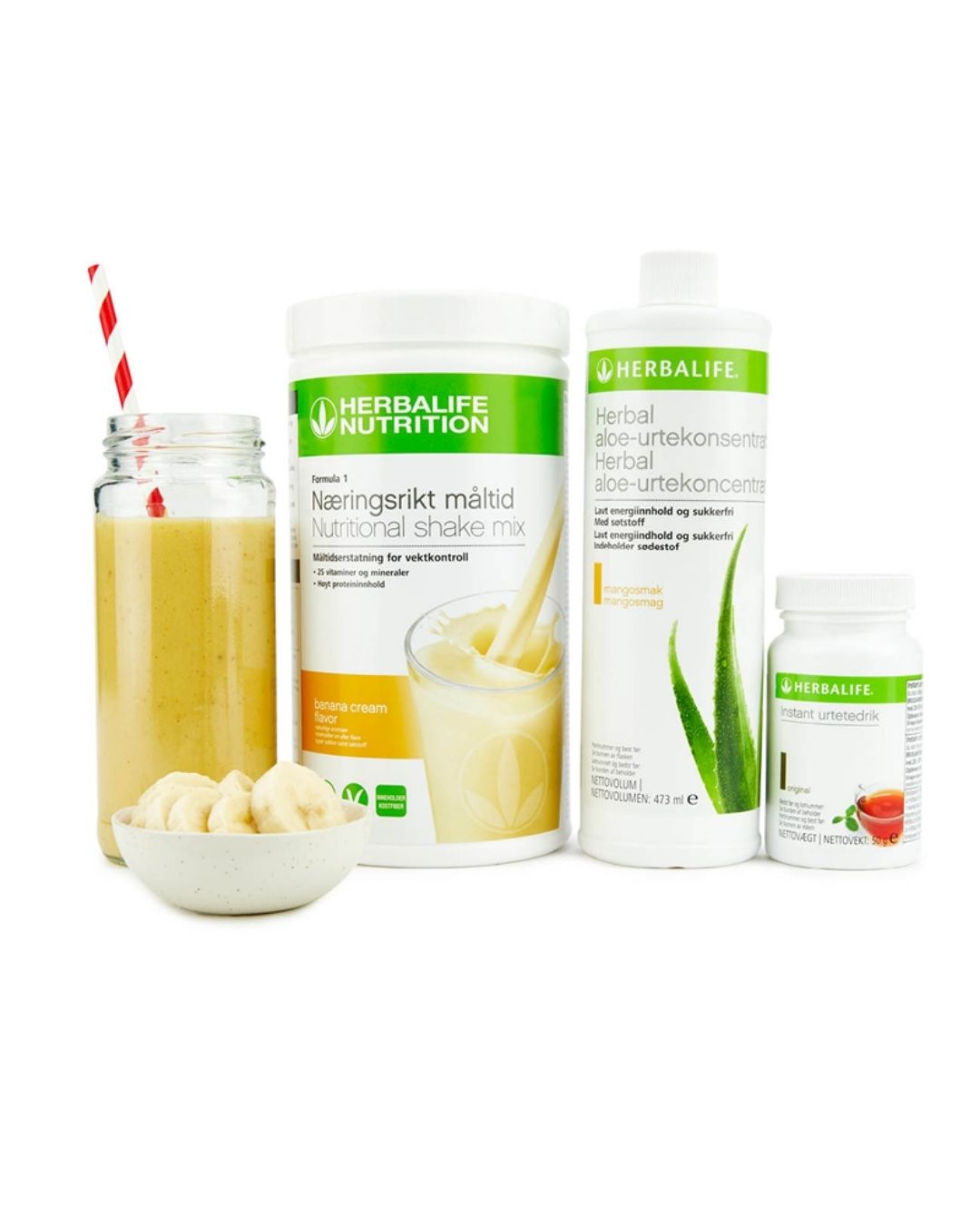 Bildet viser Herbalife-produktene som Frokostpakke basic banan består av; Herbalife-shake med banansmak, Herbal Aloe aloevera-juice med mangosmak og Instant urtete med original-smak samt en banan-shake i et glass med sugerør og noen bananskiver i en skål.