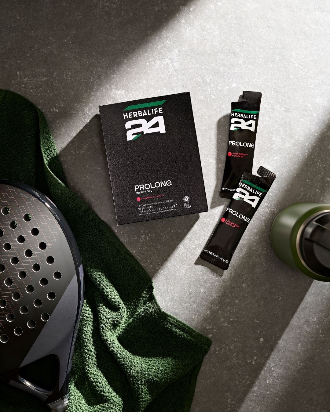 To porsjonsposer og en eske Herbalife H24 Prolong Energy Gel, et håndkle, en drikkeflaske og en racket.