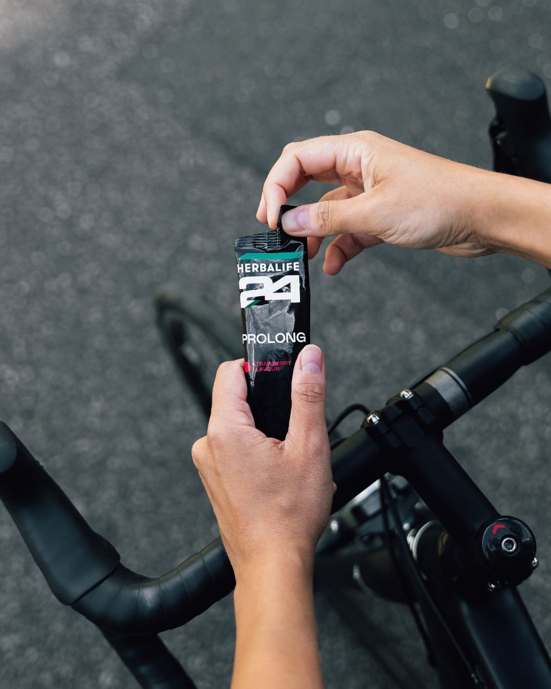 En person på sykkel holder en pose Herbalife H24 Prolong Energy Gel i hånda.