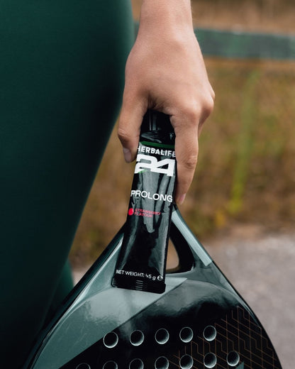 En pakke Herbalife H24 Prolong Energy Gel i hånden på en person med racket. 