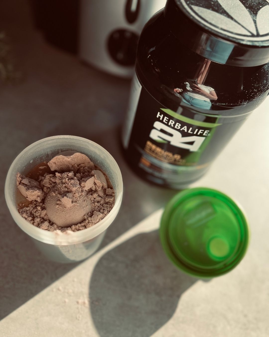 H24 Rebuild Strength boks og et ristebeger med proteinshake på en kjøkkenbenk. 