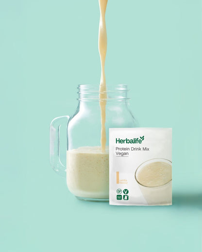 Herbalife Protein Drink Mix PDM Vegan vanilje porsjonspose med ferdig proteindrikk som helles i ei mugge.