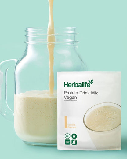 Herbalife Protein Drink Mix PDM Vegan vanilje porsjonspose med ferdig proteindrikk som helles i ei mugge.