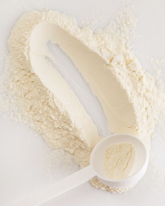 Proteinpulver og måleskje på et bord.