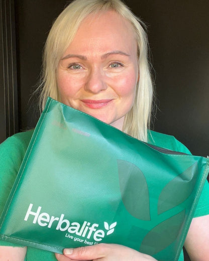 Helga Opsett holder frem en pakke Herbalife prøvepakke md shake og instant urtete.