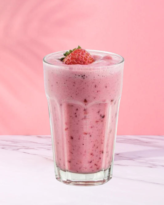 En rosa Herbalife-smoothie i et glass med et friskt jordbær på toppen. Rosa bakgrunn.