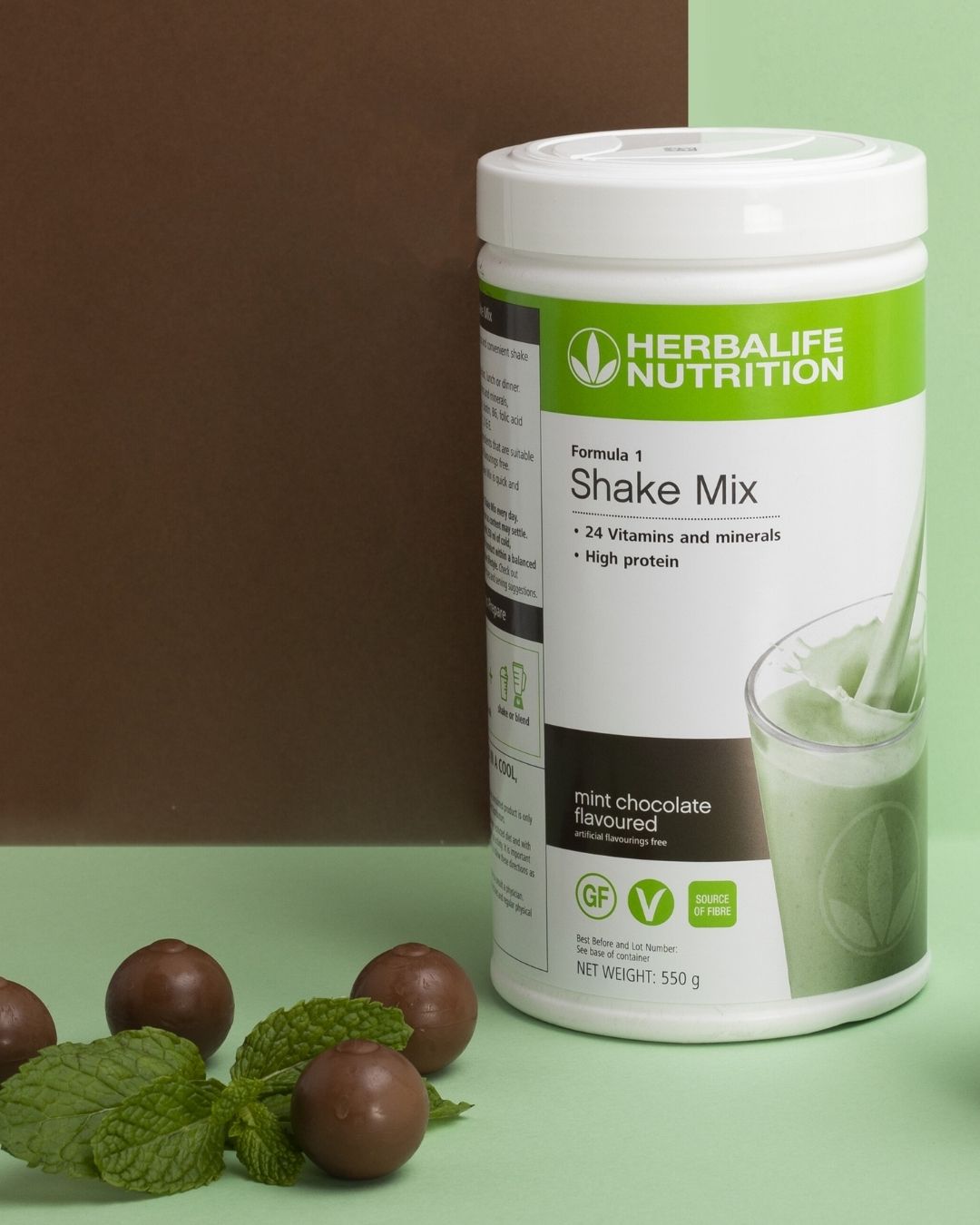 En boks Herbalife Formula 1 shakemix med Mint chocolate-smak og noen sjokoladekuler sammen med mintblader.