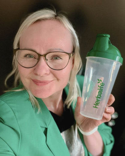 Shakerflaske med Herbalife-logo og Helga Opsett som holder den i handa. 