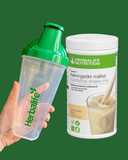 Vanilje Herbalife shake-boks og shakerflaske i hånden på grønn bakgrunn, Frokostshake.no. 